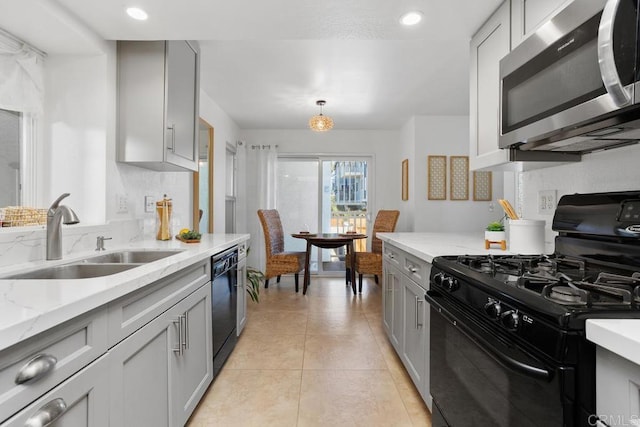 kitchen with pendant lighting, sink, gray cabinets, black appliances, and light stone countertops