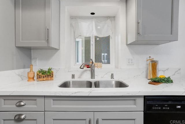 kitchen featuring gray cabinets, dishwasher, sink, and light stone countertops