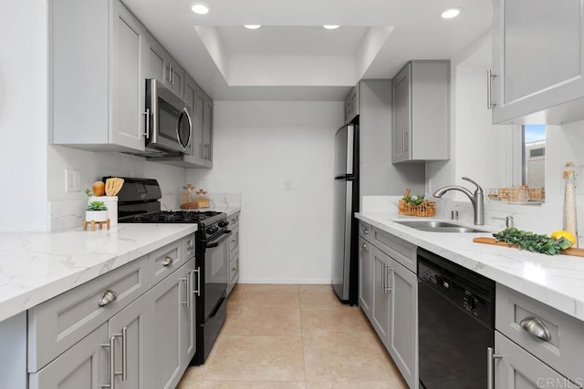 kitchen featuring sink, light tile patterned floors, light stone counters, black appliances, and a raised ceiling