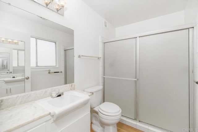 bathroom featuring vanity, toilet, and an enclosed shower