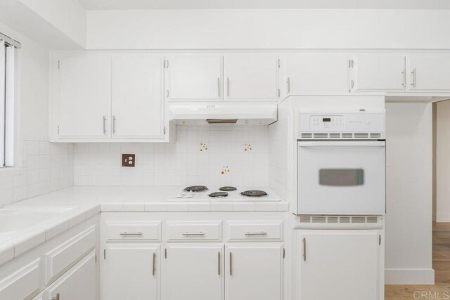 26405 Cherry Hills Blvd, Menifee, CA 92586 - kitchen featuring white appliances, tile counters, white cabinets, under cabinet range hood, and decorative backsplash