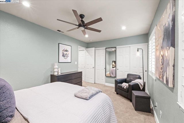 carpeted bedroom featuring two closets and ceiling fan