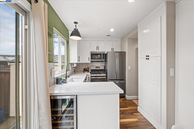 kitchen featuring pendant lighting, sink, appliances with stainless steel finishes, white cabinets, and beverage cooler