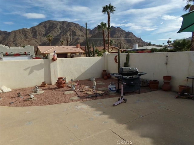 view of patio featuring a mountain view, a fenced backyard, and grilling area