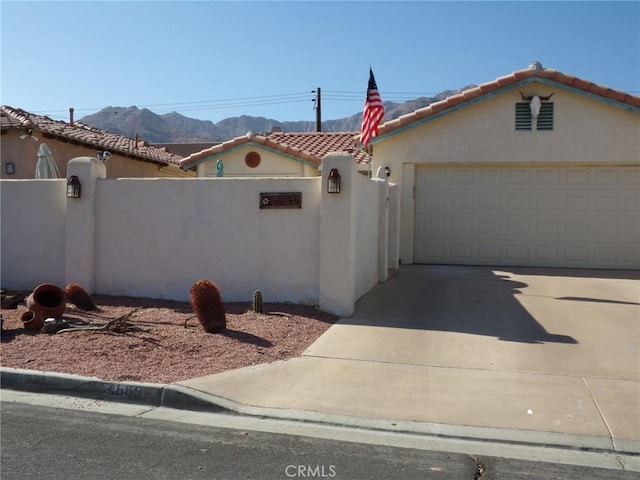 mediterranean / spanish house with stucco siding, driveway, fence, an attached garage, and a tiled roof