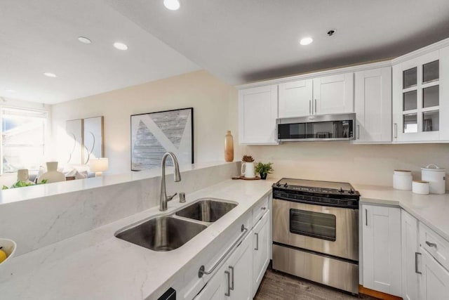 kitchen featuring stainless steel appliances, light stone countertops, sink, and white cabinets