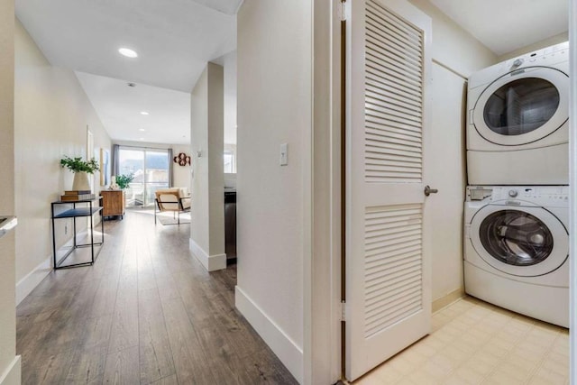 clothes washing area with stacked washer and dryer and light hardwood / wood-style flooring