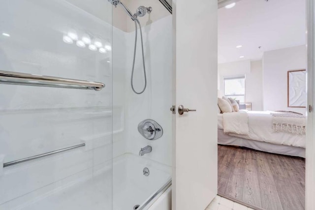 bathroom with hardwood / wood-style flooring and combined bath / shower with glass door