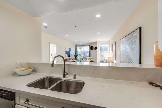 kitchen with sink, stainless steel dishwasher, and light stone counters