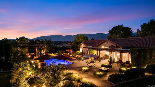 pool at dusk with a mountain view and a patio