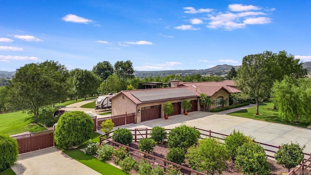 view of front of house with a garage, a mountain view, a front lawn, and solar panels