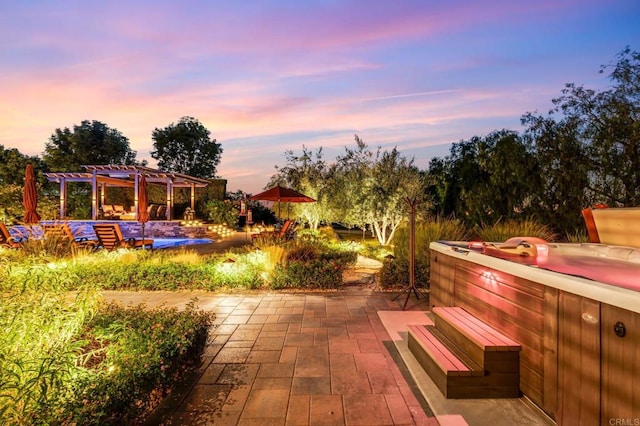 patio terrace at dusk featuring a pergola and a hot tub