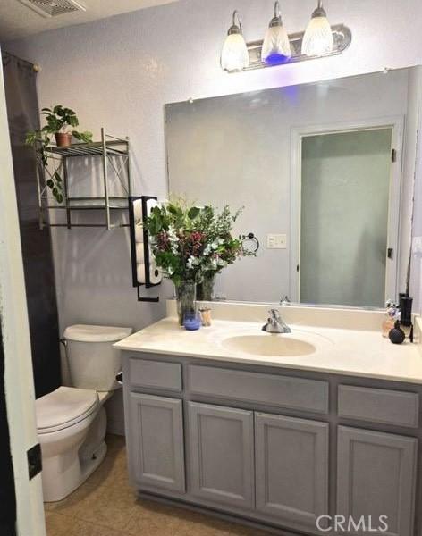 bathroom featuring toilet, visible vents, and vanity