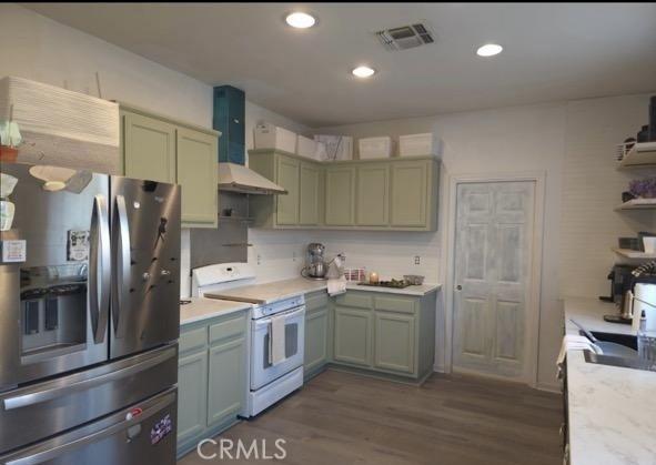 kitchen with white range oven, visible vents, light countertops, wall chimney range hood, and stainless steel fridge with ice dispenser