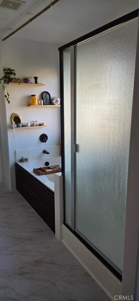 interior space with a stall shower, visible vents, and a garden tub