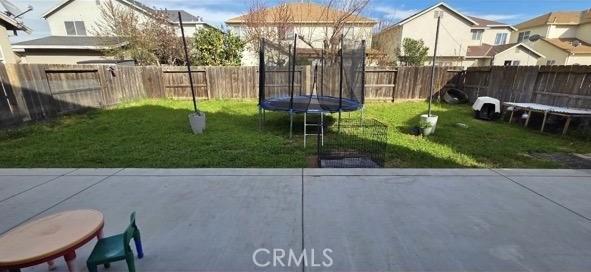 84 Jack Ct, Merced, CA 95341 - fenced backyard with a trampoline, a patio area, and a residential view
