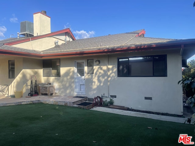 rear view of property with cooling unit, a lawn, and a patio area