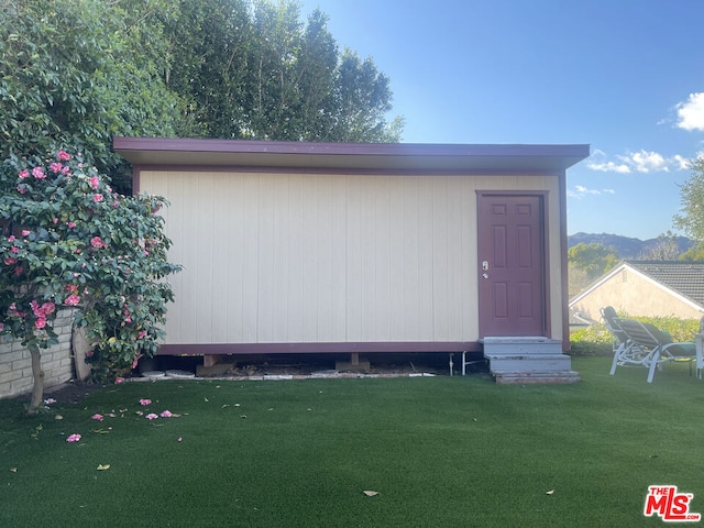 view of outdoor structure with a mountain view and a lawn