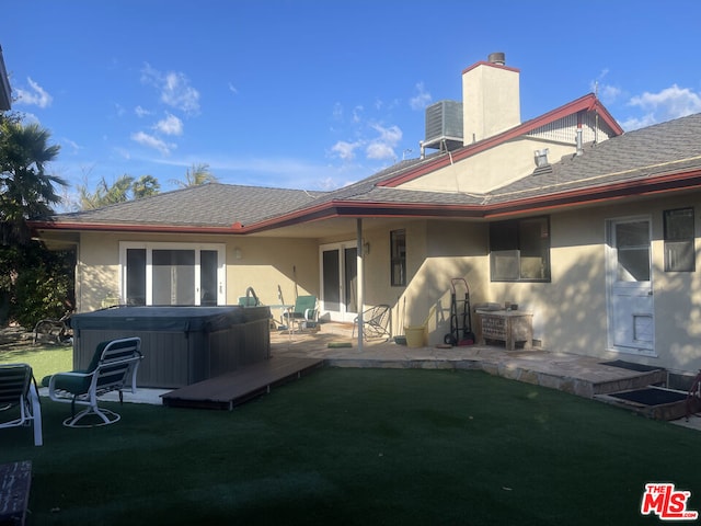 back of property with a yard, a hot tub, central AC unit, and a patio area