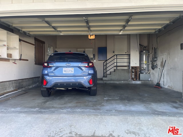 garage with a garage door opener, electric panel, and strapped water heater