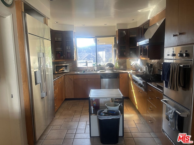 kitchen with appliances with stainless steel finishes, sink, wall chimney range hood, and backsplash