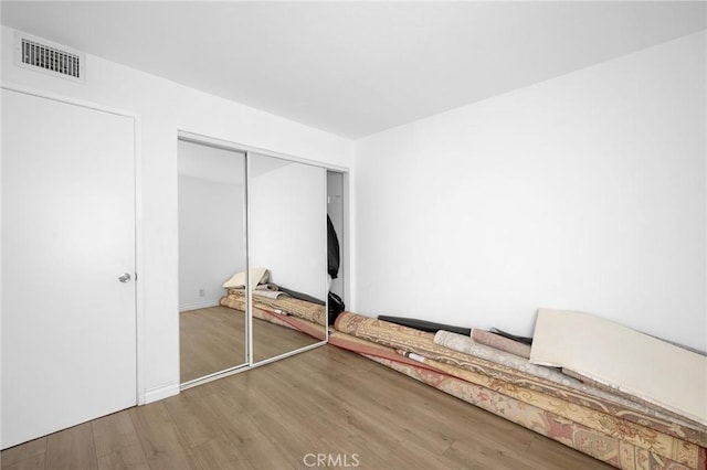 unfurnished bedroom with wood-type flooring and a closet