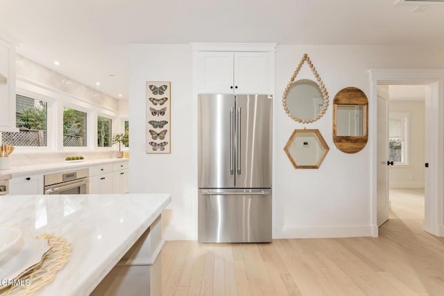 kitchen with stainless steel appliances, light wood-type flooring, and white cabinets