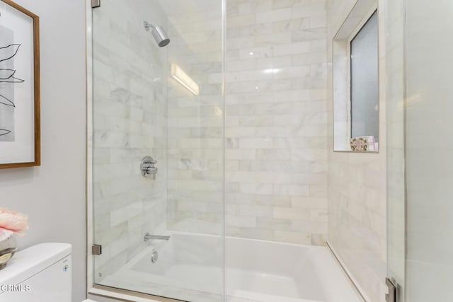 bathroom with toilet and combined bath / shower with glass door