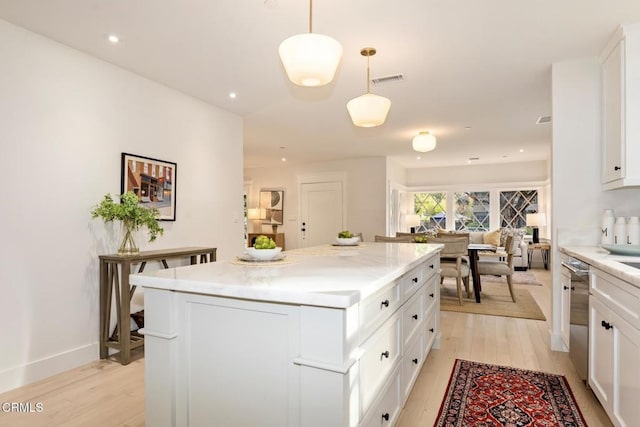 kitchen featuring pendant lighting, dishwasher, white cabinets, a center island, and light hardwood / wood-style floors