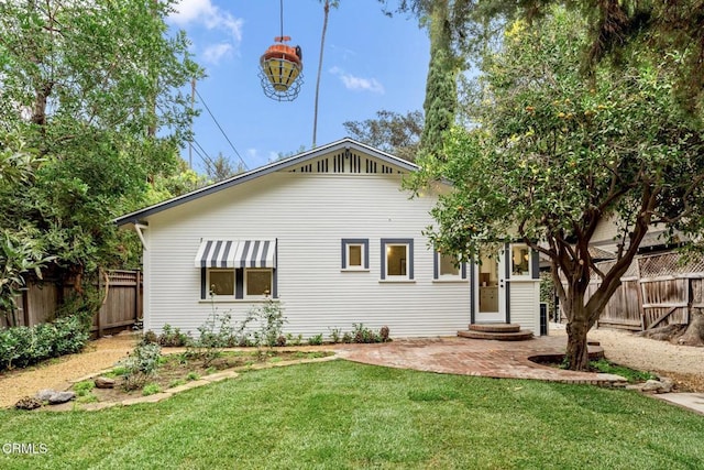 back of house with a lawn and a patio