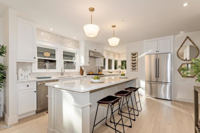 kitchen featuring hanging light fixtures, stainless steel appliances, sink, and white cabinets