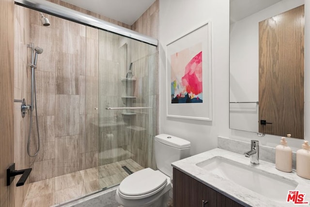 bathroom featuring vanity, an enclosed shower, and toilet