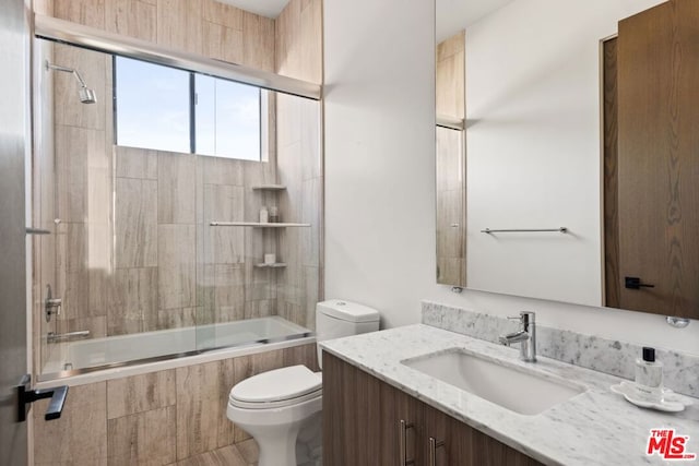 full bathroom featuring tiled shower / bath, vanity, and toilet