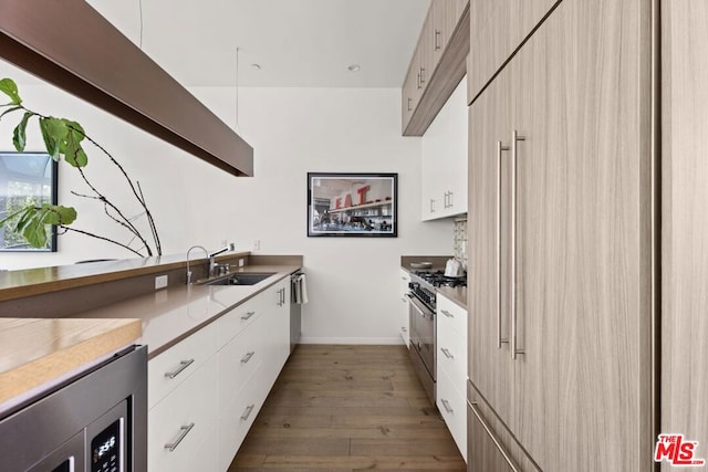 kitchen featuring dark hardwood / wood-style floors, sink, white cabinets, and high end range