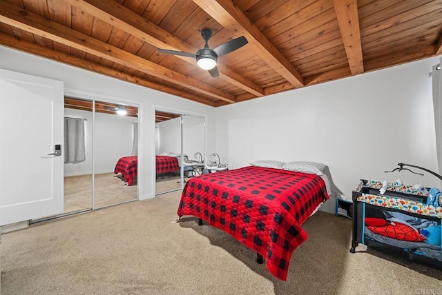 bedroom with beamed ceiling, carpet flooring, ceiling fan, multiple closets, and wooden ceiling