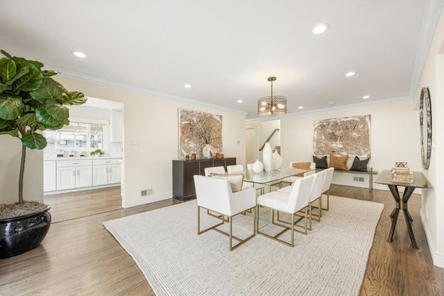 dining space featuring crown molding, a chandelier, and light wood-type flooring