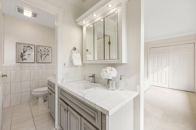 bathroom featuring tile walls, tile patterned flooring, ornamental molding, vanity, and toilet