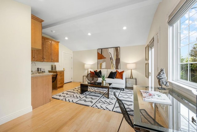 living room with lofted ceiling, sink, a wealth of natural light, and light hardwood / wood-style floors