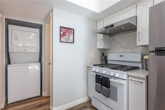 kitchen with white cabinets, stacked washer and clothes dryer, white gas range, and exhaust hood