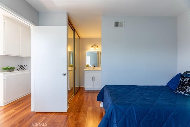 bedroom featuring ensuite bathroom, sink, and light hardwood / wood-style floors