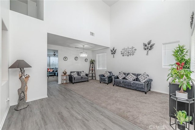 living room featuring a towering ceiling, ceiling fan, and light hardwood / wood-style flooring