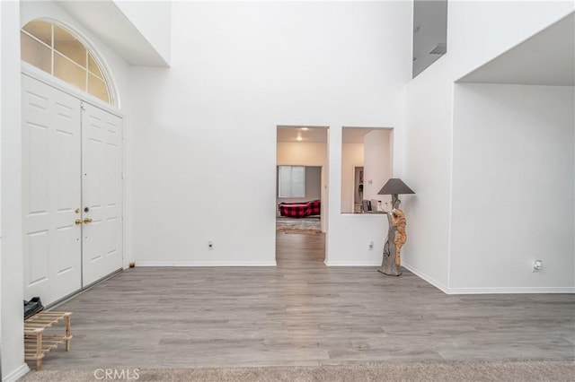 foyer entrance featuring a towering ceiling and light wood-type flooring