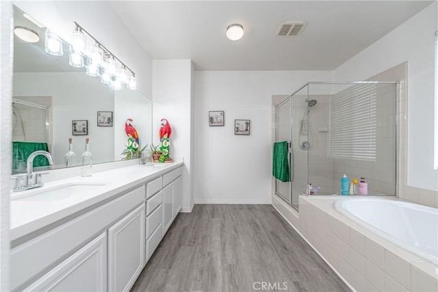 bathroom featuring plus walk in shower, wood-type flooring, and vanity