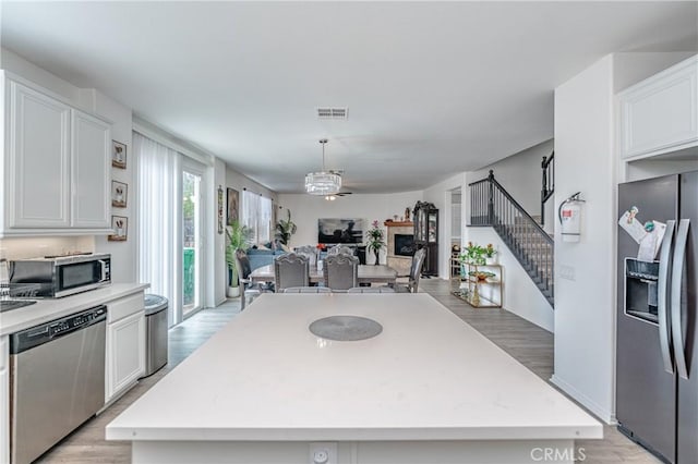 kitchen with appliances with stainless steel finishes, a kitchen island, and white cabinets