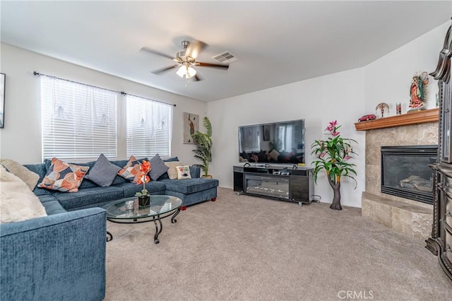 living room featuring ceiling fan, a fireplace, and light carpet