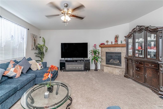 living room featuring a tiled fireplace, light colored carpet, and ceiling fan