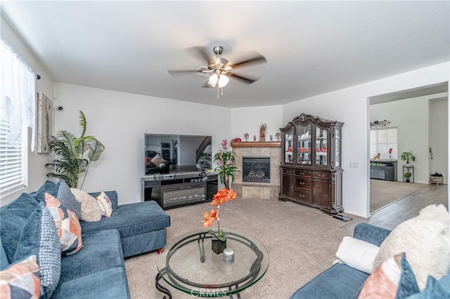 carpeted living room featuring ceiling fan and a tiled fireplace