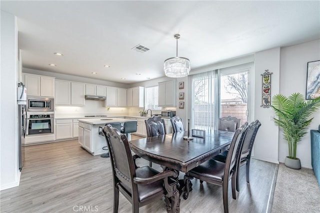 dining room featuring a notable chandelier, light hardwood / wood-style flooring, and sink