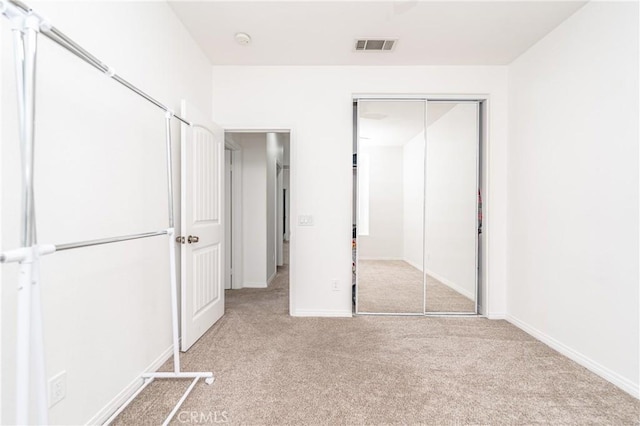 unfurnished bedroom with white refrigerator, light colored carpet, and a closet