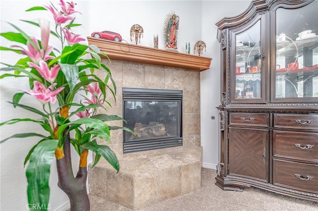 interior details with a tile fireplace and carpet flooring